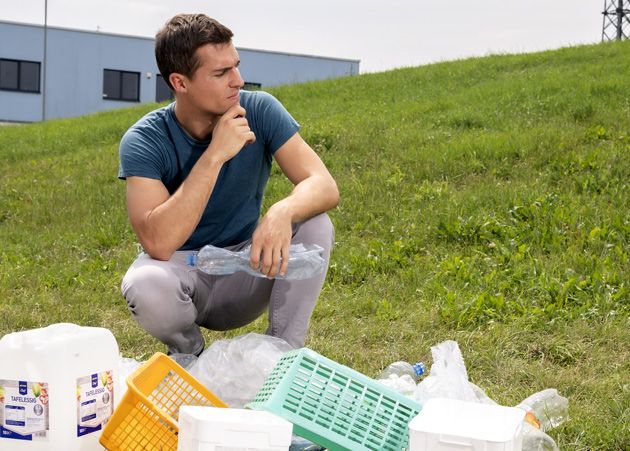 Mann in der Natur vor einem Haufen Plastikabfllen